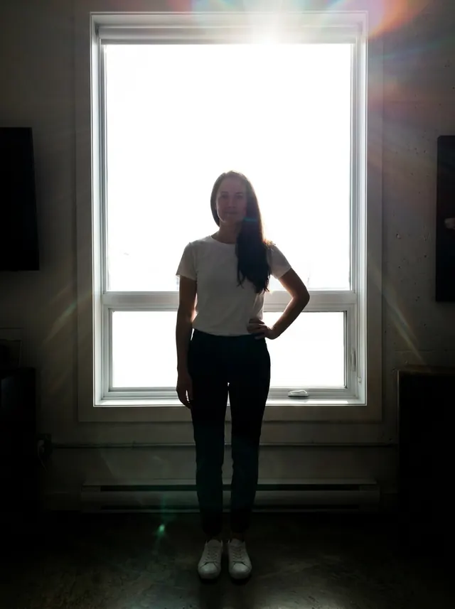 The same woman standing in front of a bright window, her body dark and underexposed